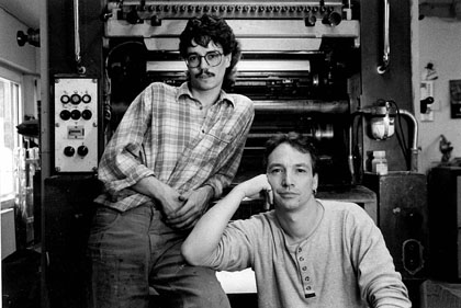 (Foto Jörg + ich) li. Jörg Rahm, Druckermeister re. Bertram Michael Rahm, Schriftsetzermeister Firmeninhaber seit 1997. Die Druckmaschine ist eine Planeta 50x70 Ein-Farben-Druckmaschine. Die Technik wurde 2000 verschrottet. Auf ihr wurde 1990 das Asbach-Buch aus Anlass ”200 Jahre Markrecht Asbach“ gedruckt. Das Foto stammt aus 1997.